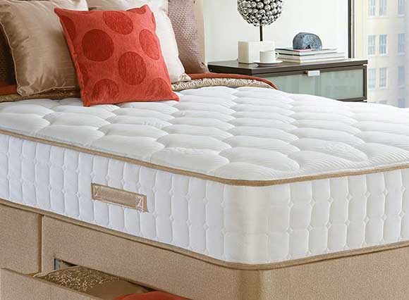 thick mattress on bed with cushions on top